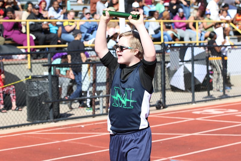 Special Olympics Colorado holds baton in triumph during track meet.